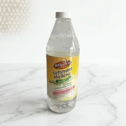 Flacon transparent de Nettoyant Miellerie BeeNOVE, capuchon gris, étiquette jaune et végétale sur marbre blanc.